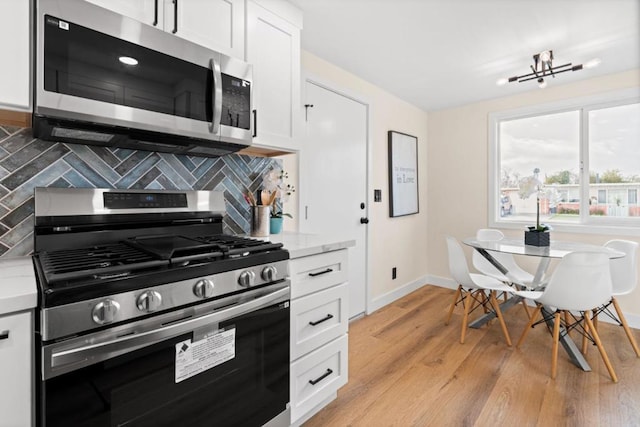 kitchen featuring white cabinets, decorative backsplash, appliances with stainless steel finishes, and light hardwood / wood-style floors