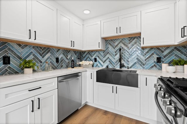 kitchen featuring white cabinets, appliances with stainless steel finishes, decorative backsplash, sink, and light hardwood / wood-style flooring