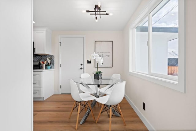 dining area featuring a wealth of natural light, a notable chandelier, and light wood-type flooring