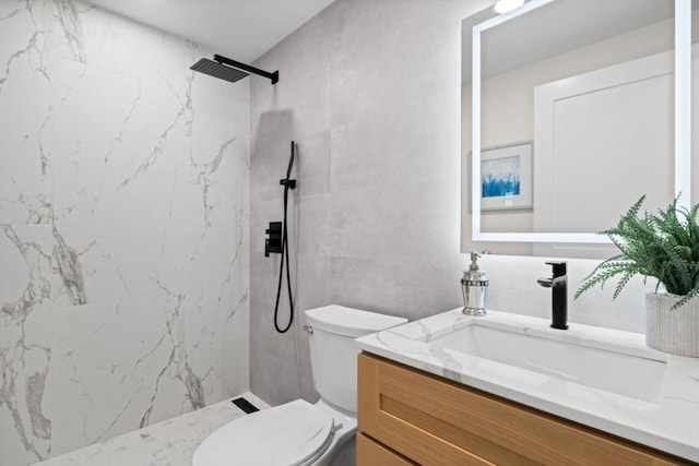 bathroom featuring toilet, tile walls, tiled shower, and vanity