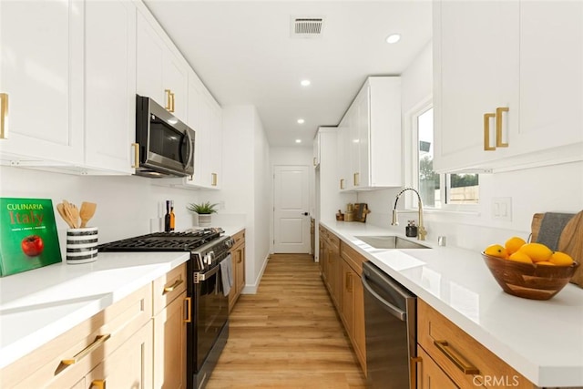 kitchen featuring stainless steel appliances, light hardwood / wood-style floors, white cabinetry, and sink