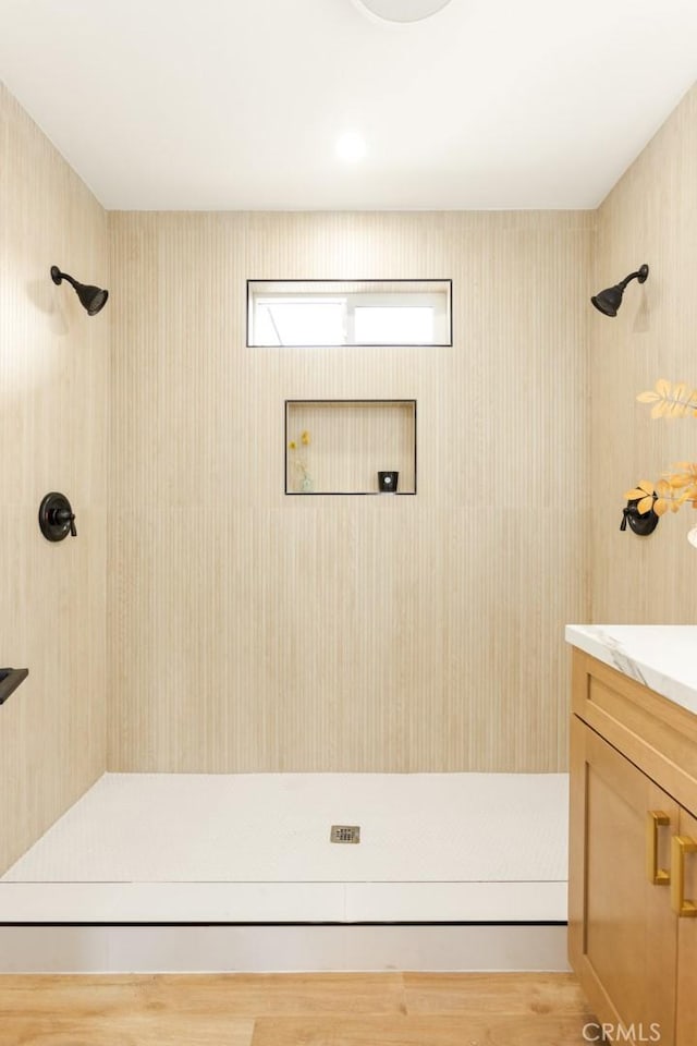 bathroom featuring hardwood / wood-style floors, vanity, and a tile shower