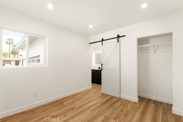 unfurnished bedroom featuring light wood-type flooring, a closet, and a barn door