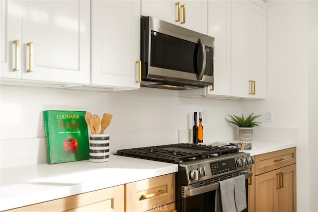 kitchen featuring light brown cabinets, stainless steel appliances, and white cabinetry