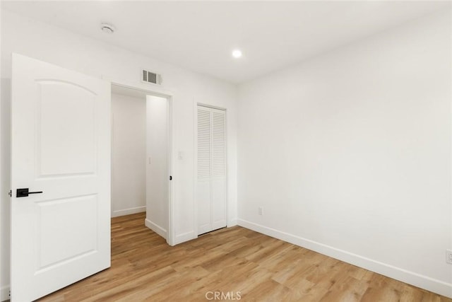 unfurnished bedroom with a closet and light hardwood / wood-style floors