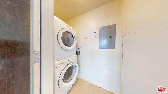 laundry room featuring stacked washer and dryer, light tile patterned floors, and electric panel