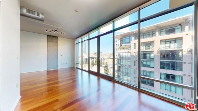 empty room with floor to ceiling windows and hardwood / wood-style floors