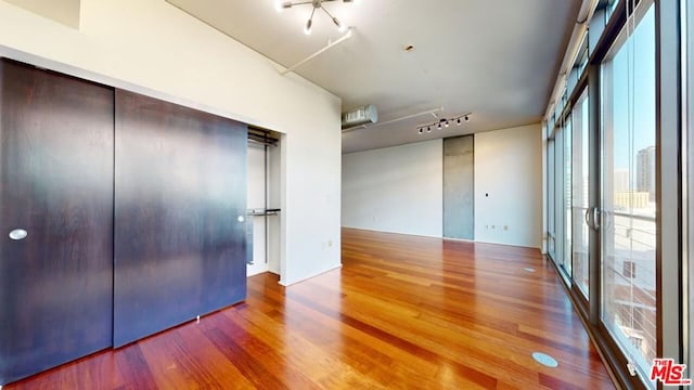 unfurnished bedroom with a closet, track lighting, and hardwood / wood-style flooring