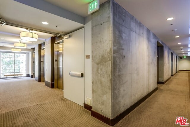 corridor featuring elevator and carpet flooring