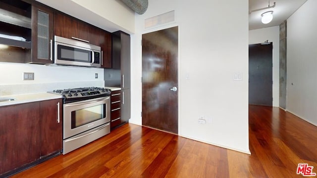 kitchen with appliances with stainless steel finishes, dark hardwood / wood-style floors, and dark brown cabinets