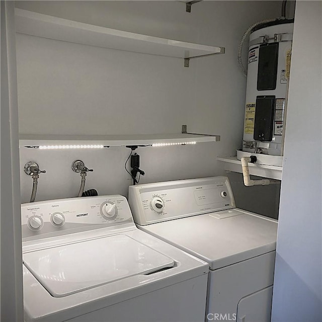 clothes washing area featuring laundry area, washing machine and dryer, and electric water heater