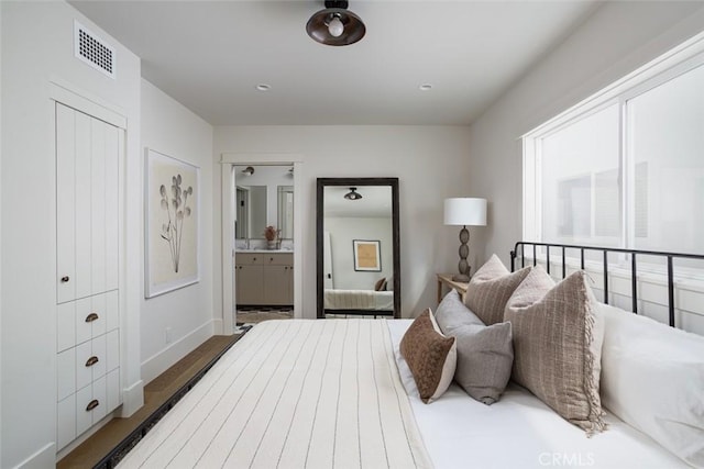 bedroom featuring connected bathroom and hardwood / wood-style flooring