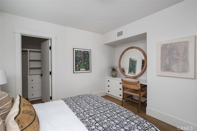 bedroom featuring a spacious closet, a closet, and dark wood-type flooring