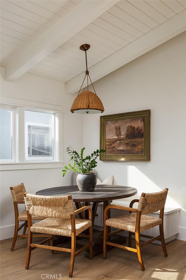 dining area with wood-type flooring, a wealth of natural light, and beamed ceiling