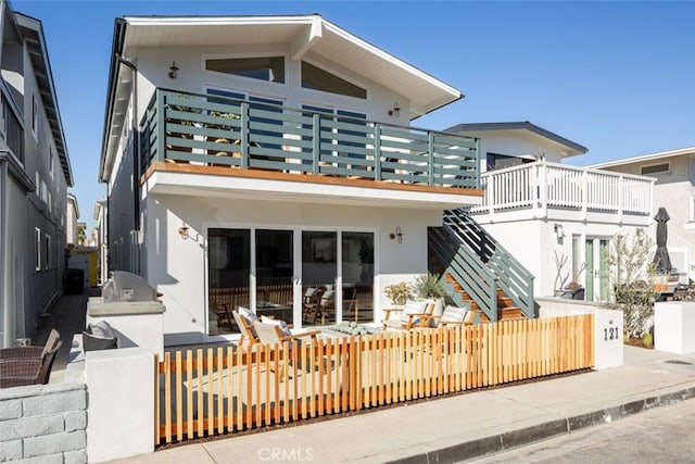 rear view of house featuring a balcony and an outdoor kitchen