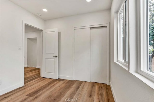 unfurnished bedroom with light hardwood / wood-style flooring and a closet