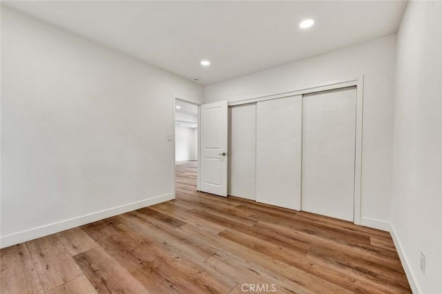 unfurnished bedroom with a closet and light wood-type flooring