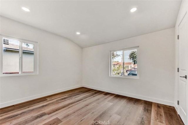 empty room featuring lofted ceiling, a wealth of natural light, and light wood-type flooring