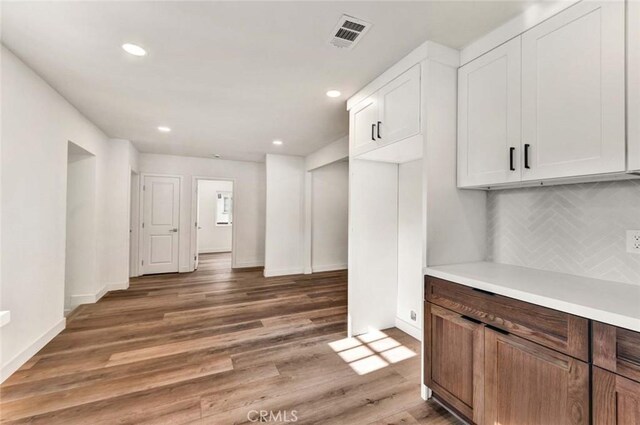 kitchen with white cabinetry, dark hardwood / wood-style floors, and backsplash