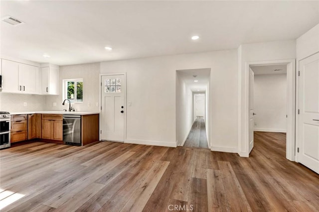 kitchen featuring white cabinetry, stainless steel dishwasher, range, and light wood-type flooring