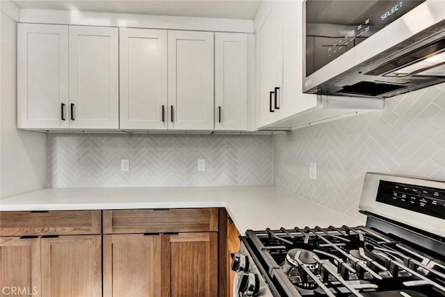 kitchen featuring stainless steel appliances, white cabinetry, and backsplash