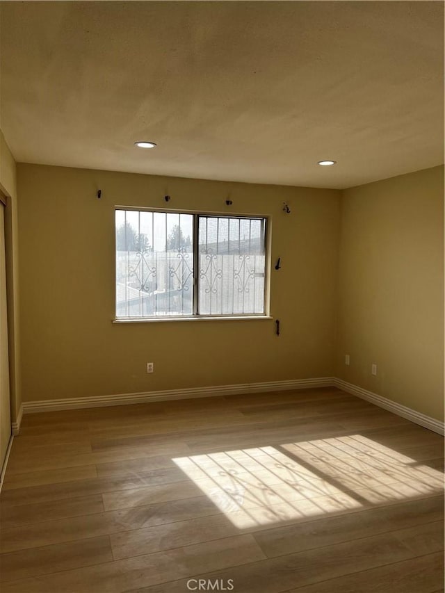 empty room with recessed lighting, light wood-style flooring, and baseboards