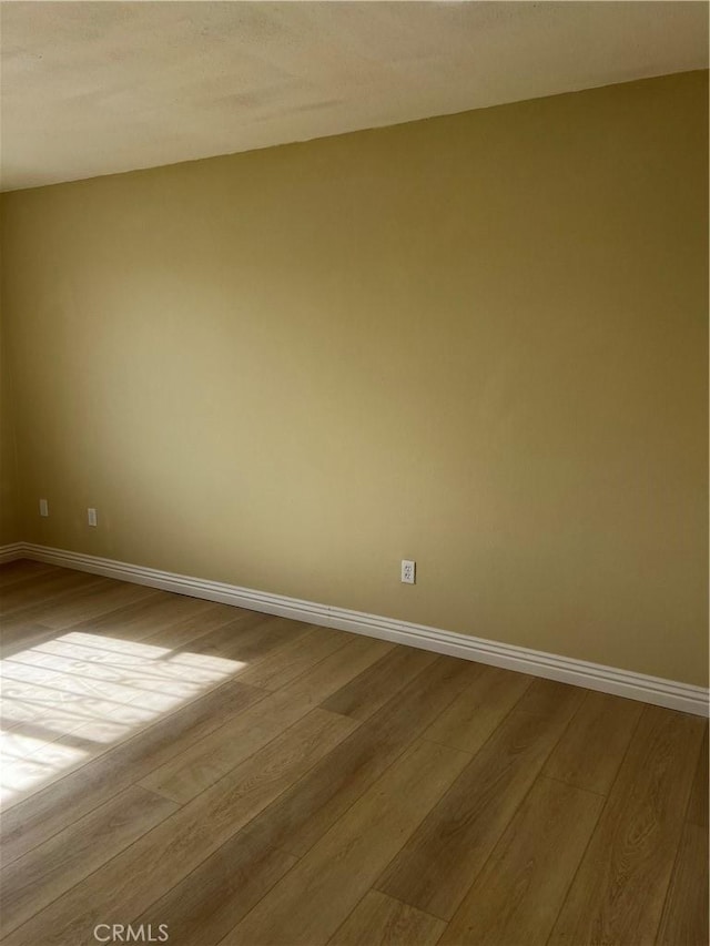 spare room featuring light wood-type flooring and baseboards