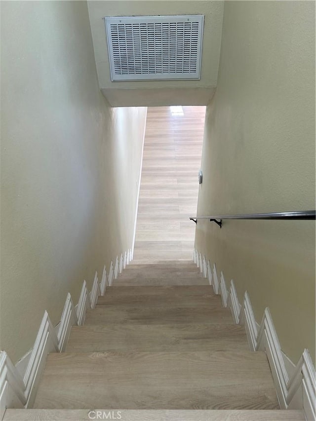 staircase with visible vents and wood finished floors