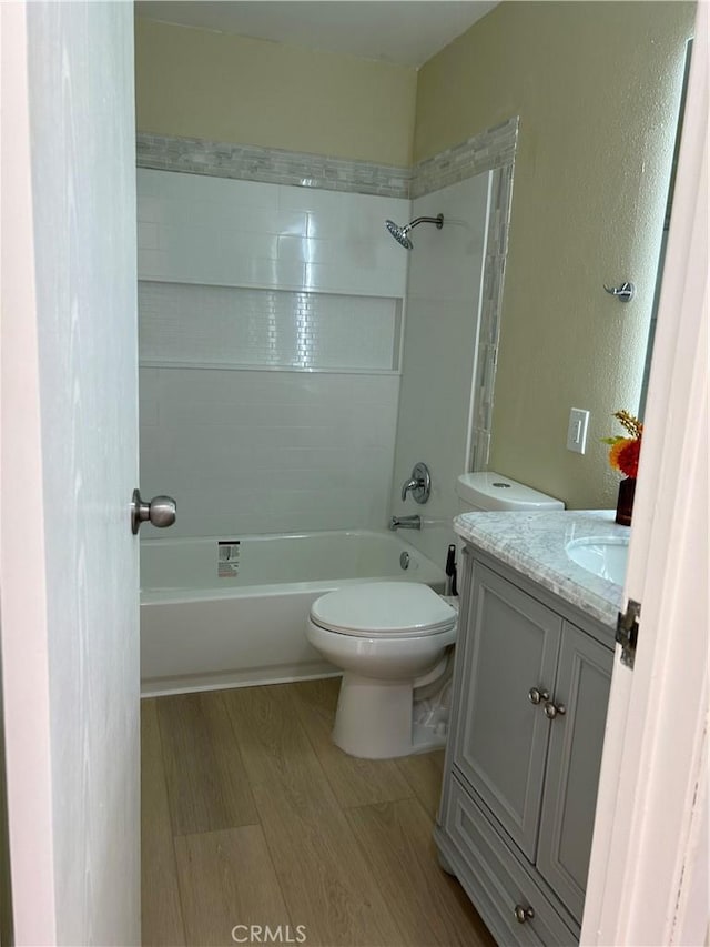 bathroom with toilet, bathing tub / shower combination, wood finished floors, and vanity