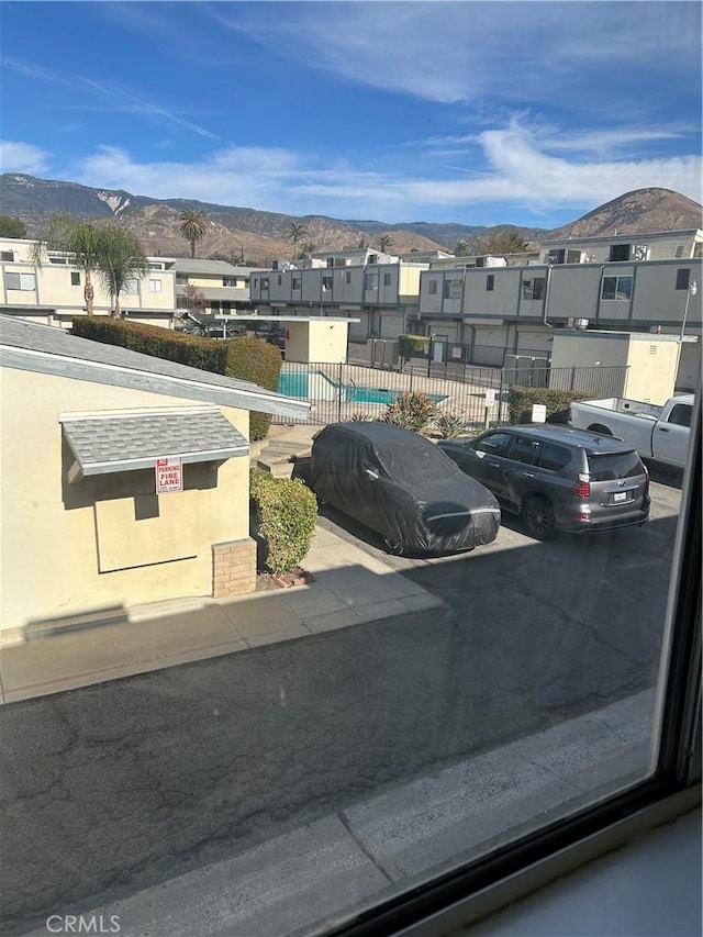 exterior space featuring a residential view, a mountain view, fence, and a community pool