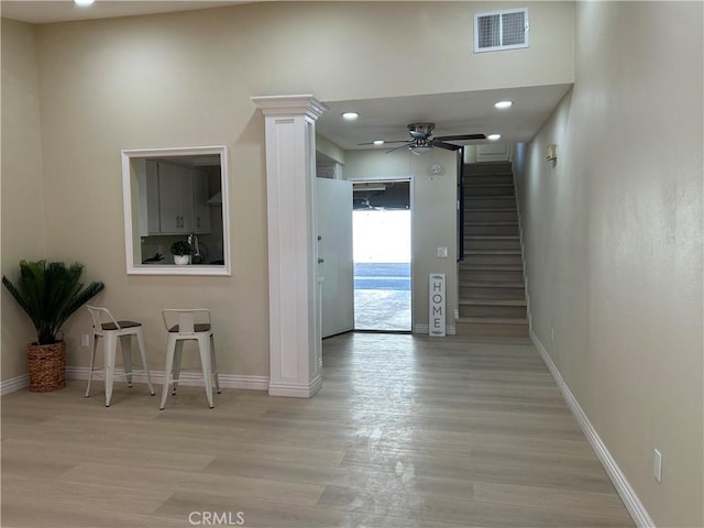 hall with visible vents, light wood-style flooring, baseboards, and stairs