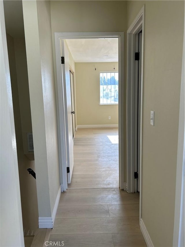 hall with baseboards and light wood-style floors