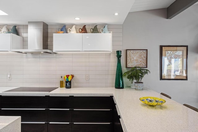 kitchen with decorative backsplash, light stone countertops, black electric stovetop, and wall chimney exhaust hood