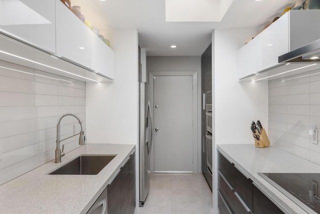 kitchen with decorative backsplash, sink, light stone countertops, stainless steel appliances, and white cabinets