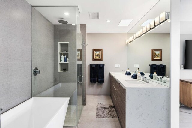 bathroom featuring tile patterned floors, vanity, a skylight, and plus walk in shower