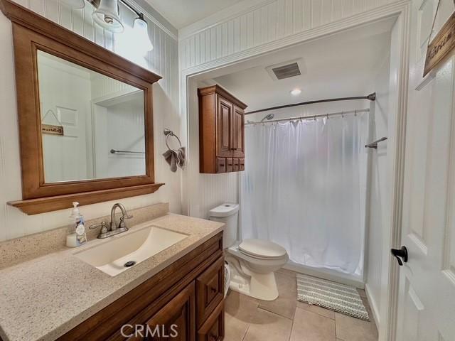 full bathroom featuring toilet, shower / bathtub combination with curtain, tile patterned floors, and vanity