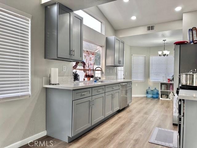 kitchen with stainless steel dishwasher, an inviting chandelier, sink, and gray cabinetry