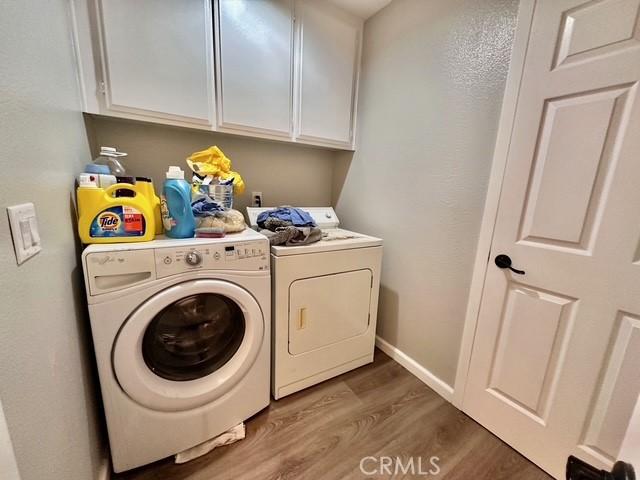 clothes washing area with cabinets, dark hardwood / wood-style floors, and separate washer and dryer