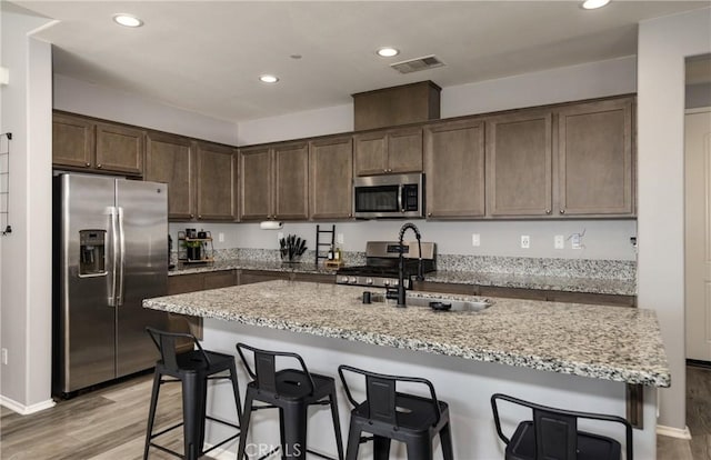 kitchen featuring light stone counters, sink, a center island with sink, and stainless steel appliances