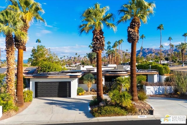 view of front of property with a mountain view, a garage, and solar panels