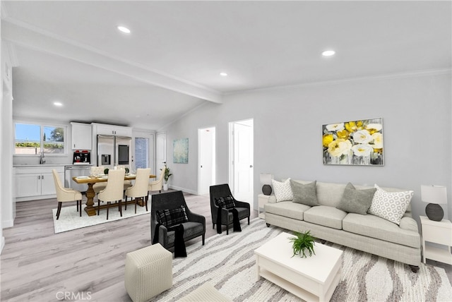 living room featuring sink, light hardwood / wood-style flooring, and lofted ceiling with beams