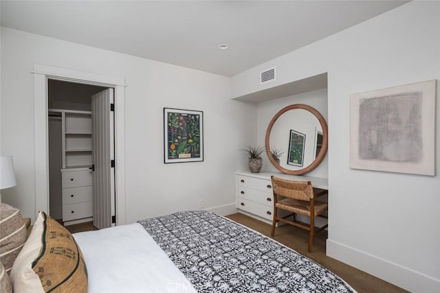 bedroom featuring a spacious closet and dark wood-type flooring