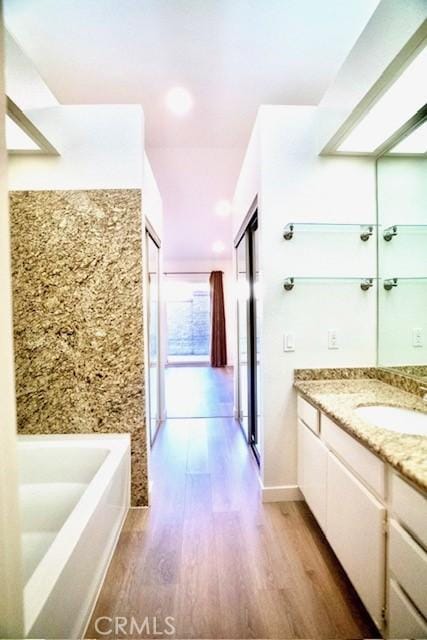 bathroom with vanity, a bath, and hardwood / wood-style floors