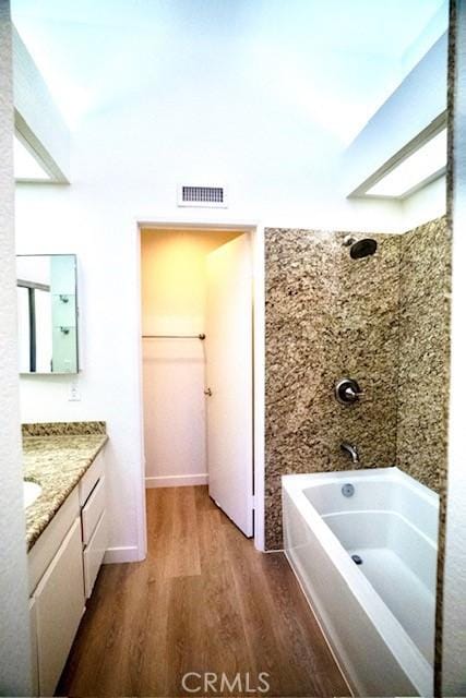 bathroom featuring hardwood / wood-style floors, vanity, and tiled shower / bath