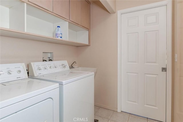 laundry room featuring washer and clothes dryer, sink, light tile patterned floors, and cabinets