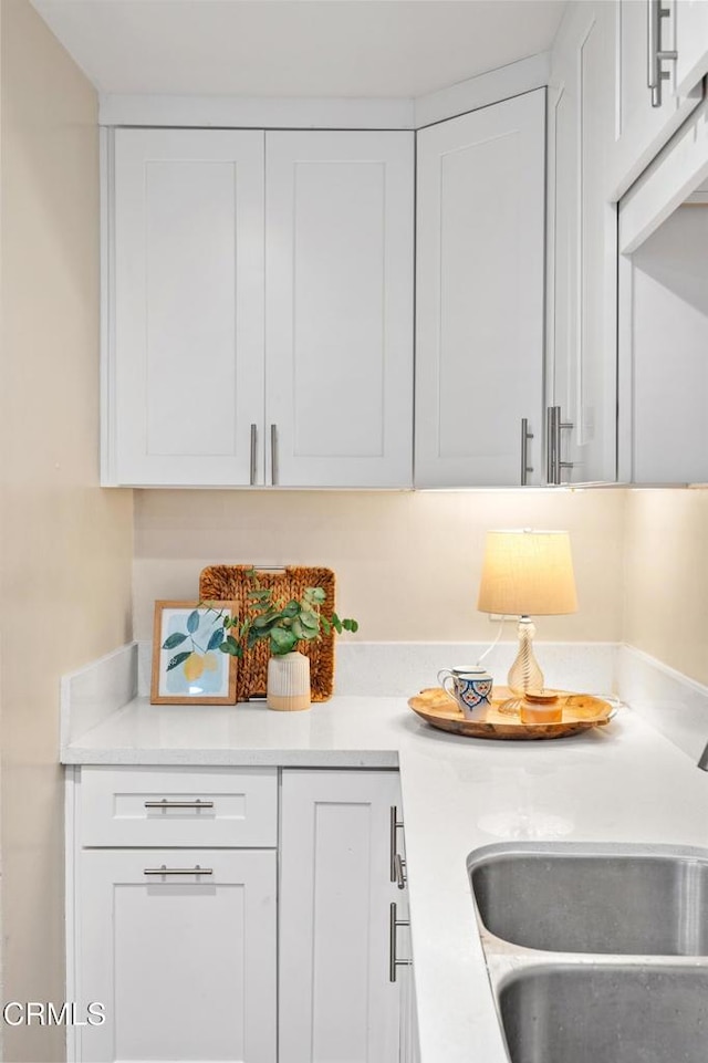 kitchen featuring a sink, light countertops, and white cabinetry