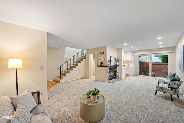 living room with a glass covered fireplace, baseboards, recessed lighting, stairs, and carpet