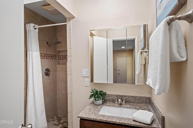 full bathroom featuring tiled shower and vanity