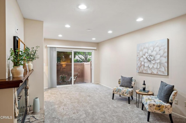 living area featuring recessed lighting, baseboards, a fireplace with raised hearth, and carpet floors