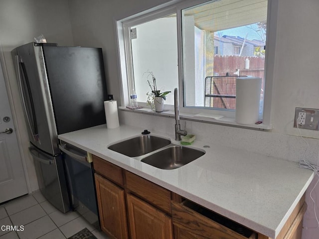 kitchen featuring sink, light tile patterned floors, stainless steel refrigerator, and dishwasher